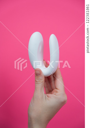 Woman holding white curved sex toy on pink background.  122381861