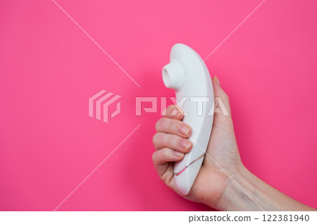 Woman holding white vacuum clitoral vibrator on pink background. Woman holding white vacuum clitoral vibrator on pink background. 122381940