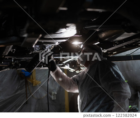 The master sprays an anti-corrosion compound on the bottom of the car. The master sprays an anti-corrosion compound on the bottom of the car. 122382024