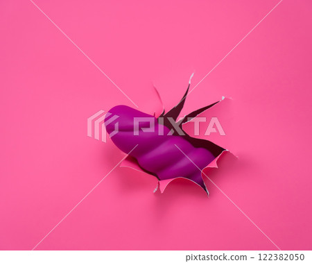 Raspberry sex toy sticks out of pink paper background. Raspberry sex toy sticks out of pink paper background. 122382050