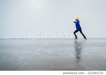Caucasian woman in a blue sweater is skating on a frozen lake. The figure skater performs the program. Caucasian woman in a blue sweater is skating on a frozen lake. The figure skater performs the program. 122382135