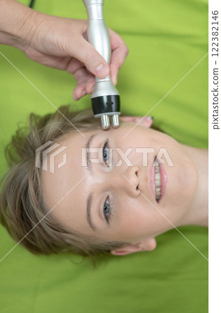 Top view of Caucasian woman undergoing radio wave RF lifting procedure in beauty salon. Top view of Caucasian woman undergoing radio wave RF lifting procedure in beauty salon. 122382146
