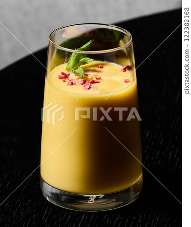 Indulge in a deliciously creamy Mango Lassi with a beautiful garnish for a delightful treat Indulge in a deliciously creamy Mango Lassi with a beautiful garnish for a delightful treat 122382168