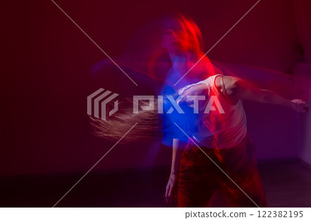 A young woman dances contemporary dances in blue and red light. Long exposure photo. A young woman dances contemporary dances in blue and red light. Long exposure photo. 122382195