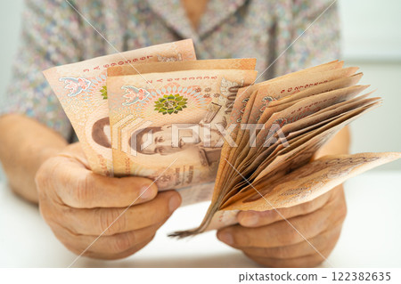 Asian elder senior woman patient holding Thai banknotes money in her hand, Cost of living and medical care. 122382635