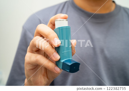 Asthma and chronic obstructive pulmonary disease COPD, Asian young man using metered dose inhaler MDI. Asthma and chronic obstructive pulmonary disease COPD, Asian young man using metered dose inhaler MDI. 122382735