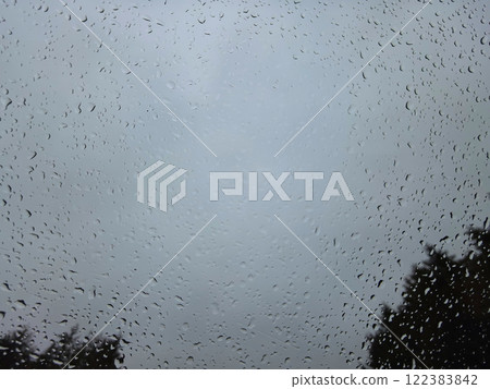 Raindrops dance on a window against a moody sky in a tranquil moment 122383842
