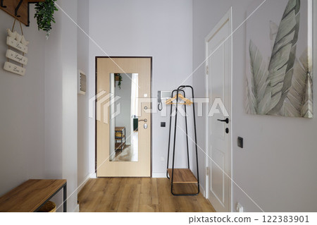 A Stylish and Modern Entryway featuring an Attractive Mirror and a Functional Coat Rack 122383901