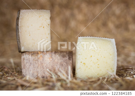 Whole head of ripe country cheese and slices on hay Whole head of ripe country cheese and slices on hay 122384185