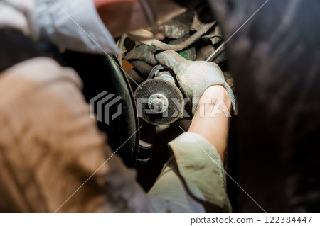 Mechanic Working on a Car Engine with Precision in a Dimly Lit Garage 122384447