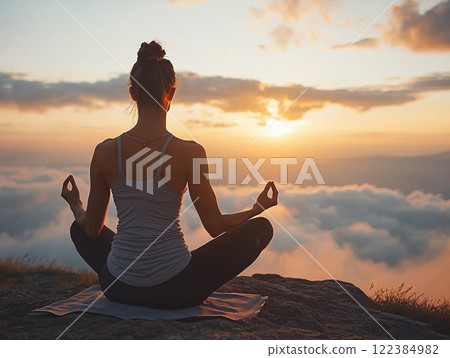 Person practicing yoga in a serene outdoor location at sunrise 122384982