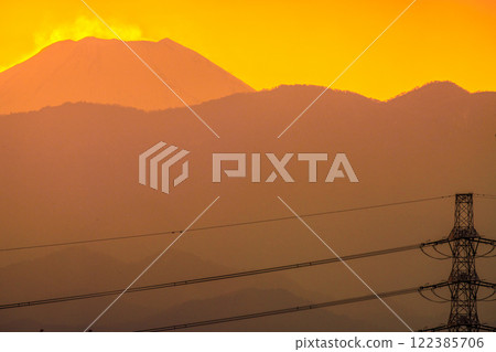 Tokyo cityscape in Japan. Sky is dyed orange... View of power towers and transmission lines. Mount Fuji in the background on the left. January 28, 2025. 122385706