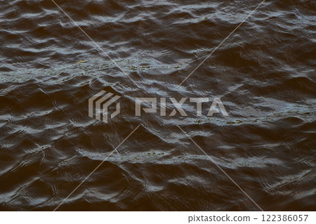 A calm water surface gently rippled by soft waves, illuminated beautifully by natural light 122386057