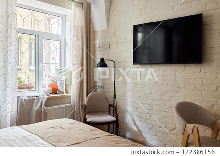 A Cozy and Modern Bedroom with Television, Abundant Natural Light, and Stylish Decor 122386156