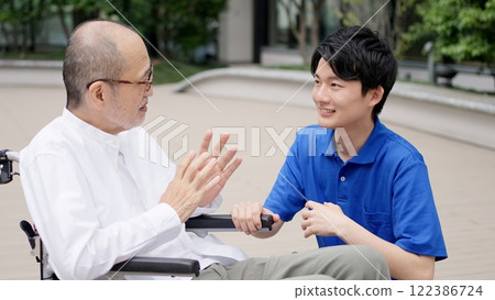 Caregiver talking to an elderly person in a wheelchair 122386724