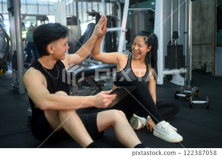 Fitness trainer and client giving each other high five after successful workout session 122387058