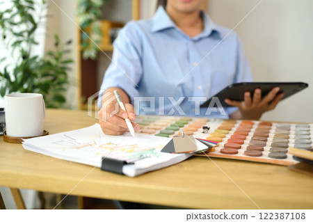 Interior designer selecting color samples while sketching design ideas on paper. 122387108