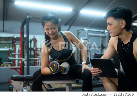 Young woman working out with personal trainer win modern gym Young woman working out with personal trainer win modern gym 122387109