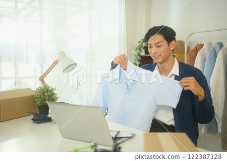 Online fashion seller presenting a product in front of his laptop 122387128