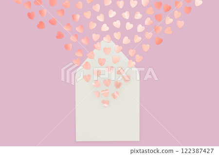 Creative minimalist composition of cream letter envelope spilling heart-shaped confetti, set against a pink background, symbolizing love and warmth. 122387427