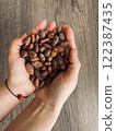 Female hands holding a handful of cocoa beans. Table top view 122387435