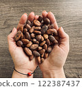 Female hands holding a handful of cocoa beans. Table top view 122387437