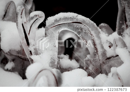 Ice covered grass curved over the ground with frozen thick layer of ice surrounded by snow with visible ice texture inside 122387673