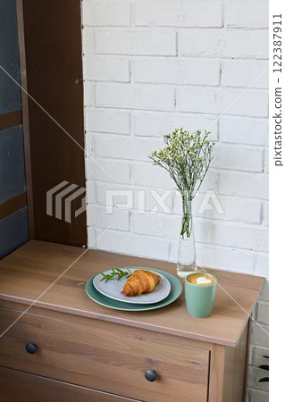 A Cozy and Inviting Breakfast Setting Featuring a Fresh Croissant and Beautiful Flowers 122387911