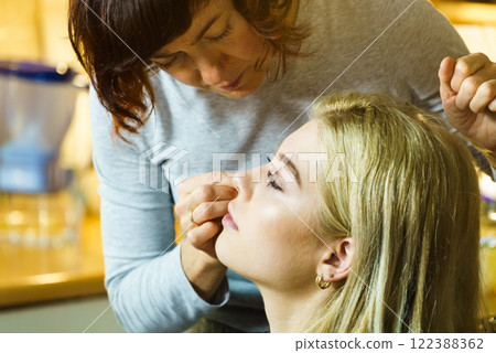 Woman getting make up from artist Woman getting make up from artist 122388362