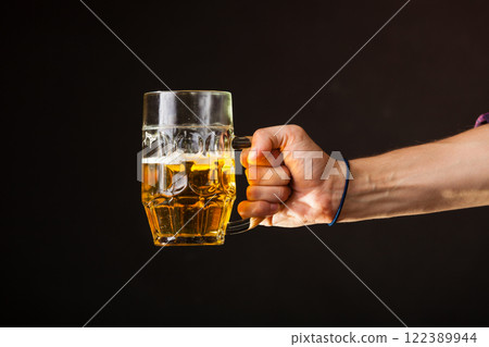 Male hand holding mug of beer Male hand holding mug of beer 122389944