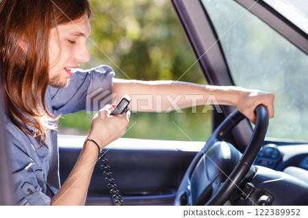 Young man driving car using cb radio 122389952