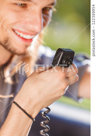 Young man driving car using cb radio 122389954