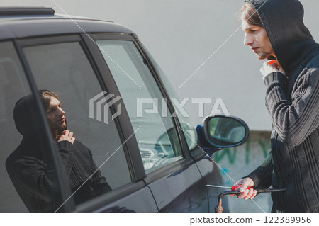Thieft man holding screwdriver breaking into car Thieft man holding screwdriver breaking into car 122389956