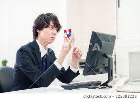 Businessman playing with Rubik's cube at work Businessman playing with Rubik's cube at work 122391228