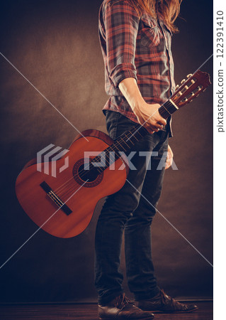 Artist is standing with guitar. 122391410