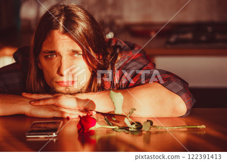 Worried man with rose and mobile phone. 122391413