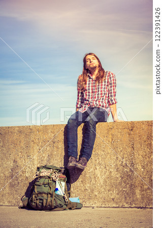 Man tourist backpacker sitting on grunge wall outdoor 122391426