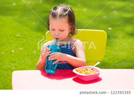 Toddler kid girl drinking eating pasta in garden Toddler kid girl drinking eating pasta in garden 122391585