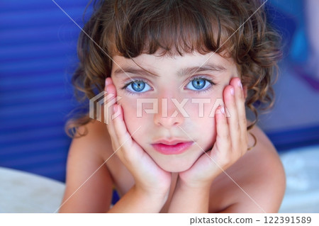 Beautiful blue eyes little girl portrait hands on face Beautiful blue eyes little girl portrait hands on face 122391589