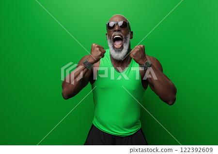 Middle-aged Black man celebrates with enthusiasm against a solid green background 122392609