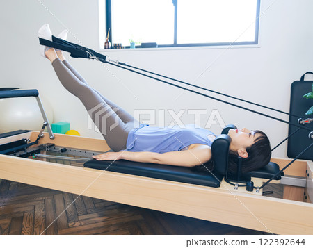 Woman doing machine pilates training Woman doing machine pilates training 122392644
