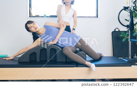 A woman taking a machine pilates lesson A woman taking a machine pilates lesson 122392647