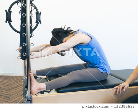 A woman taking a machine pilates lesson A woman taking a machine pilates lesson 122392652