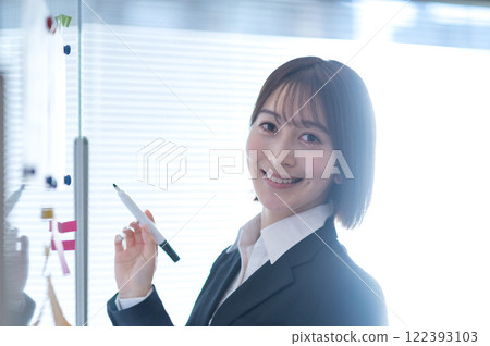 Young businesswoman writing on a whiteboard Young businesswoman writing on a whiteboard 122393103
