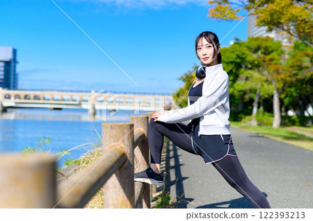 A cool woman stretching her legs on a fence along the river, walking, diet, walk, exercise 122393213