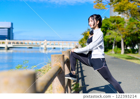 A cool woman stretching her legs on a fence along the river, walking, diet, walk, exercise 122393214