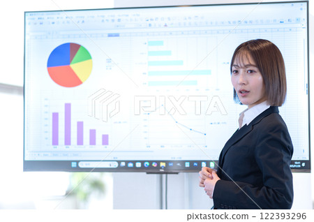 Young businesswoman giving a presentation in front of a monitor Young businesswoman giving a presentation in front of a monitor 122393296
