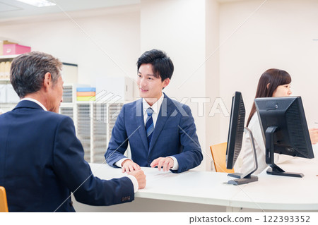 一名男子在櫃檯為老年顧客服務 122393352