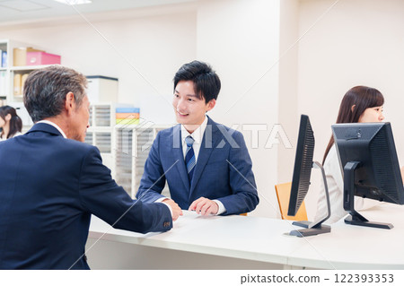 一名男子在櫃檯為老年顧客服務 122393353