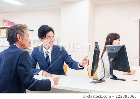 一名男子在櫃檯為老年顧客服務 122393365